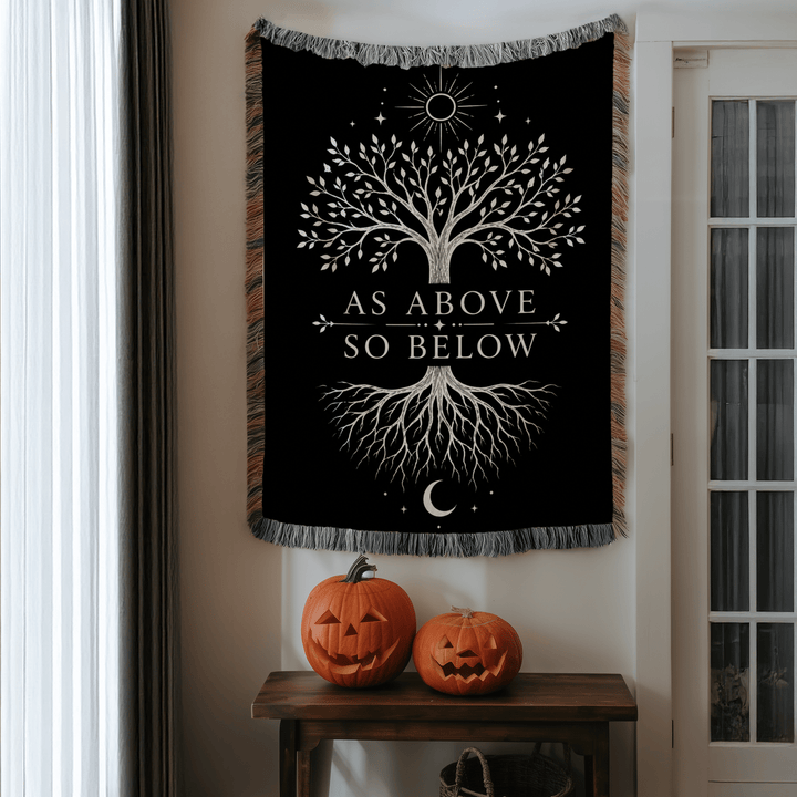 Tapestry with tree design and 'As Above So Below' text on a wall above Halloween pumpkins.