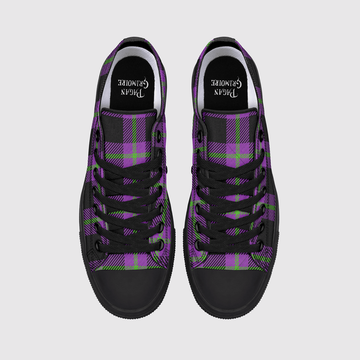 A pair of low-top canvas sneakers shown from a top-down view on a light gray background. The shoes feature a purple and black tartan plaid pattern with lime green accents, black laces, and black rubber toe caps.