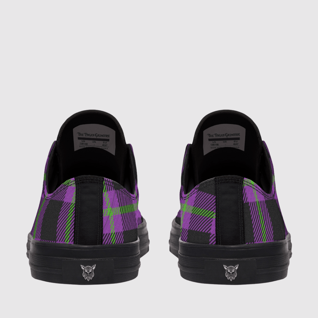 A pair of low-top sneakers shown from the back, featuring a black and purple tartan plaid pattern with lime green accents, black soles, and a small logo on the heel.