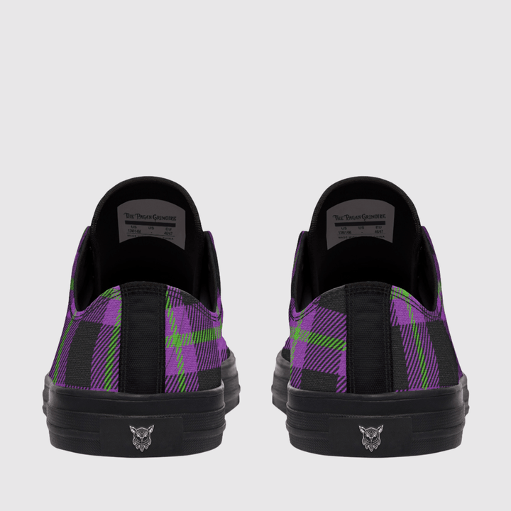 A pair of low-top sneakers shown from the back, featuring a black and purple tartan plaid pattern with lime green accents, black soles, and a small logo on the heel.