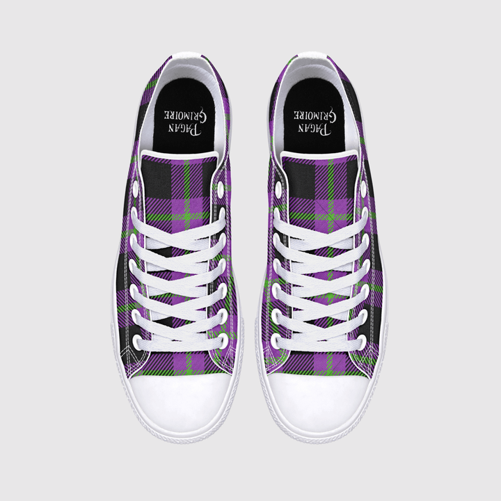 A pair of low-top sneakers shown from the back, featuring a purple, black, and green plaid pattern on the canvas uppers, a white leather heel tab, and a white rubber sole with a small logo.