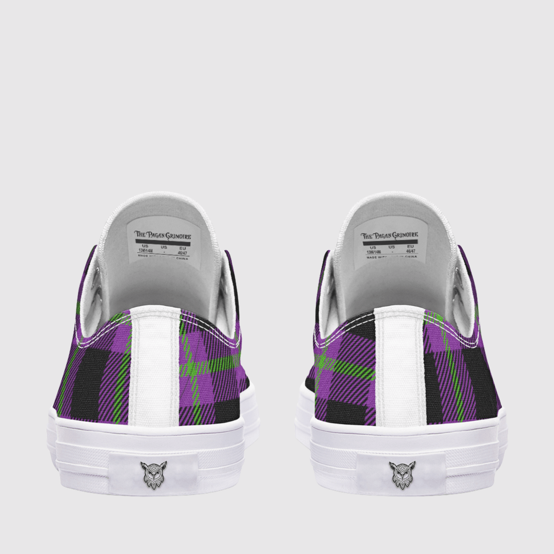 A pair of low-top sneakers shown from the back, featuring a purple, black, and green plaid pattern on the canvas uppers, a white leather heel tab, and a white rubber sole with a small logo.