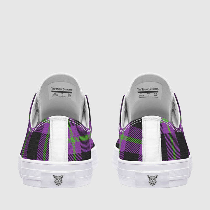 A pair of low-top sneakers shown from the back, featuring a purple, black, and green plaid pattern on the canvas uppers, a white leather heel tab, and a white rubber sole with a small logo.