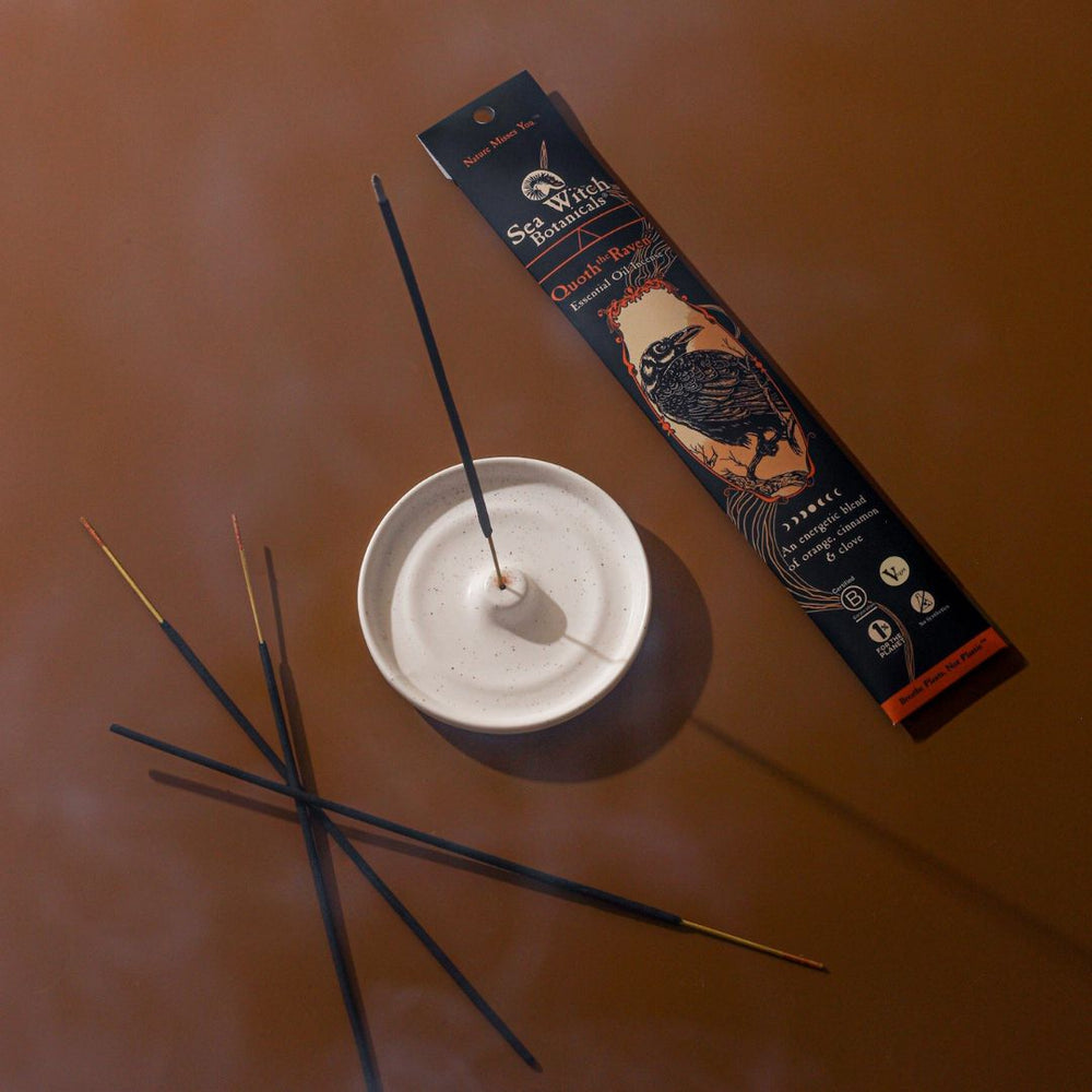Quoth the Raven Incense box beside a white dish holding several dark sticks.