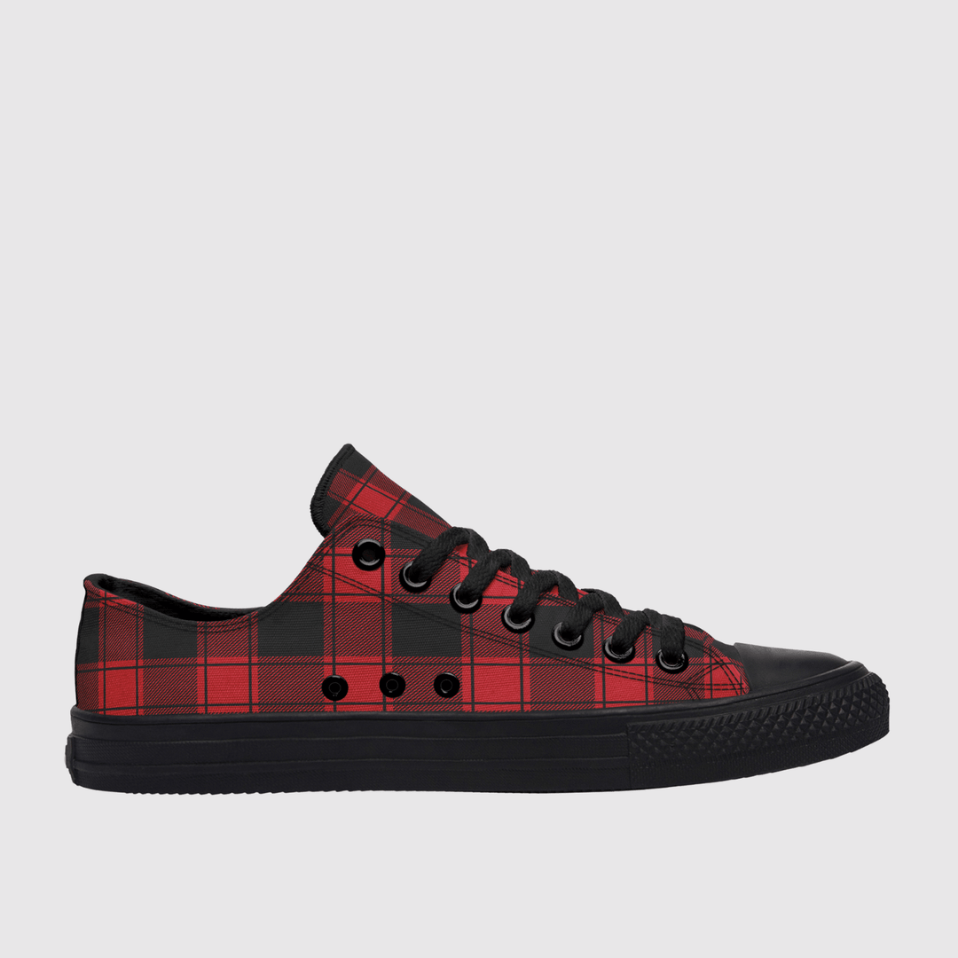 A low-top canvas sneaker featuring a red and black buffalo plaid pattern on the upper, with a solid black rubber toe cap, laces, and sole, shown against a light gray background.