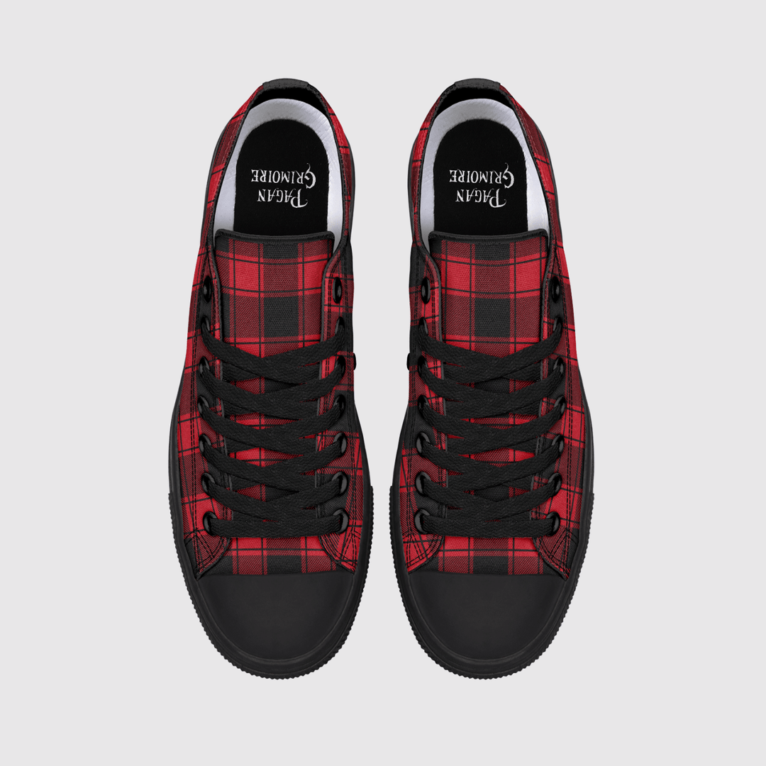 A pair of low-top canvas sneakers shown from a top-down view on a light gray background. The shoes feature a red and black tartan plaid pattern on the sides, solid black rubber toe caps and soles, black laces.
