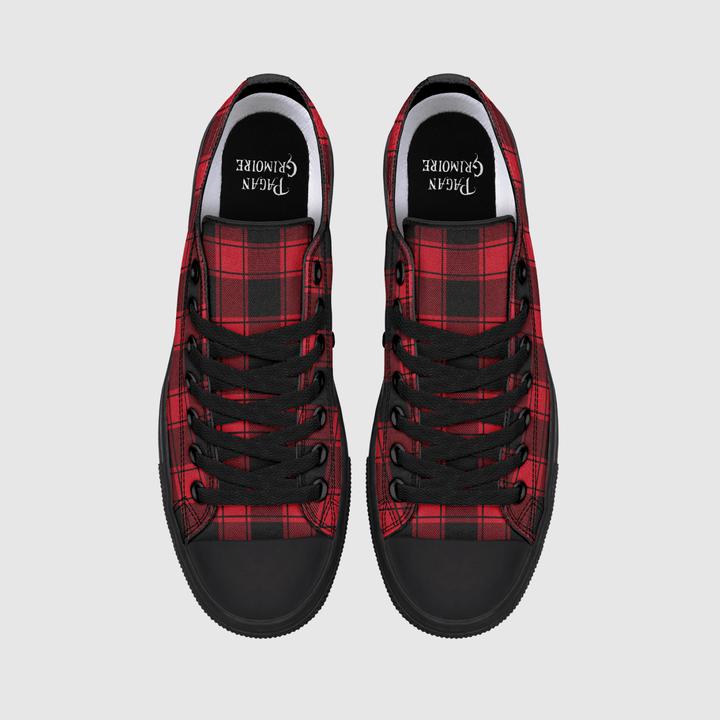 A pair of low-top canvas sneakers shown from a top-down view on a light gray background. The shoes feature a red and black tartan plaid pattern on the sides, solid black rubber toe caps and soles, black laces.