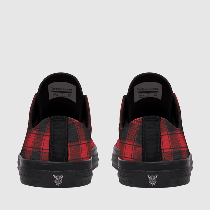 A pair of low-top sneakers shown from the back, featuring a red and black plaid pattern on the sides, solid black fabric on the heel tab, and a black sole with a small silver logo.