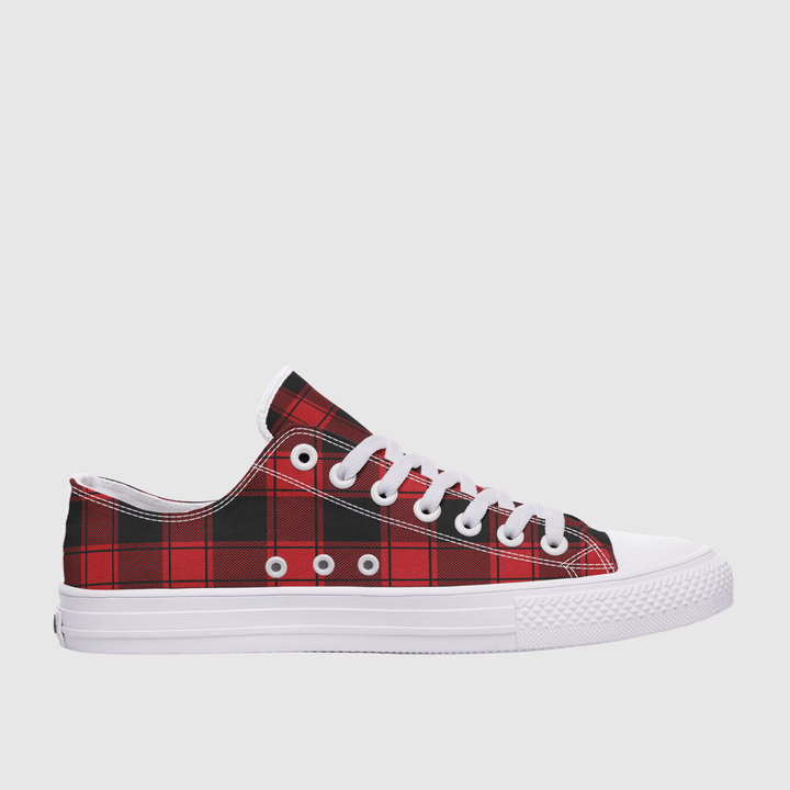 A low-top canvas sneaker featuring a red and black plaid pattern on the canvas panels, white laces, white eyelets, and a white rubber sole, shown against a light gray background.