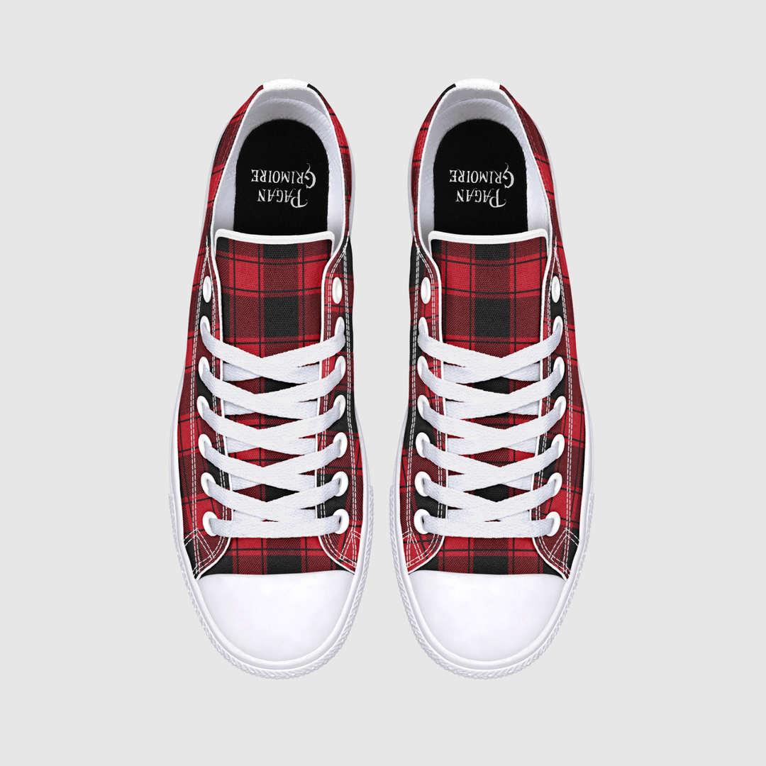 A pair of low-top canvas sneakers shown from a top-down view on a light gray background. The shoes feature a red and black tartan plaid pattern on the sides, white laces, white rubber toe caps, and a black insole.