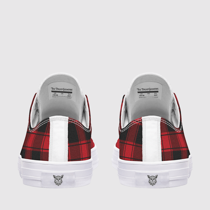 A pair of low-top sneakers shown from the back, featuring a red and black plaid pattern on the sides, a white vertical stripe, and a white rubber sole with a small logo.