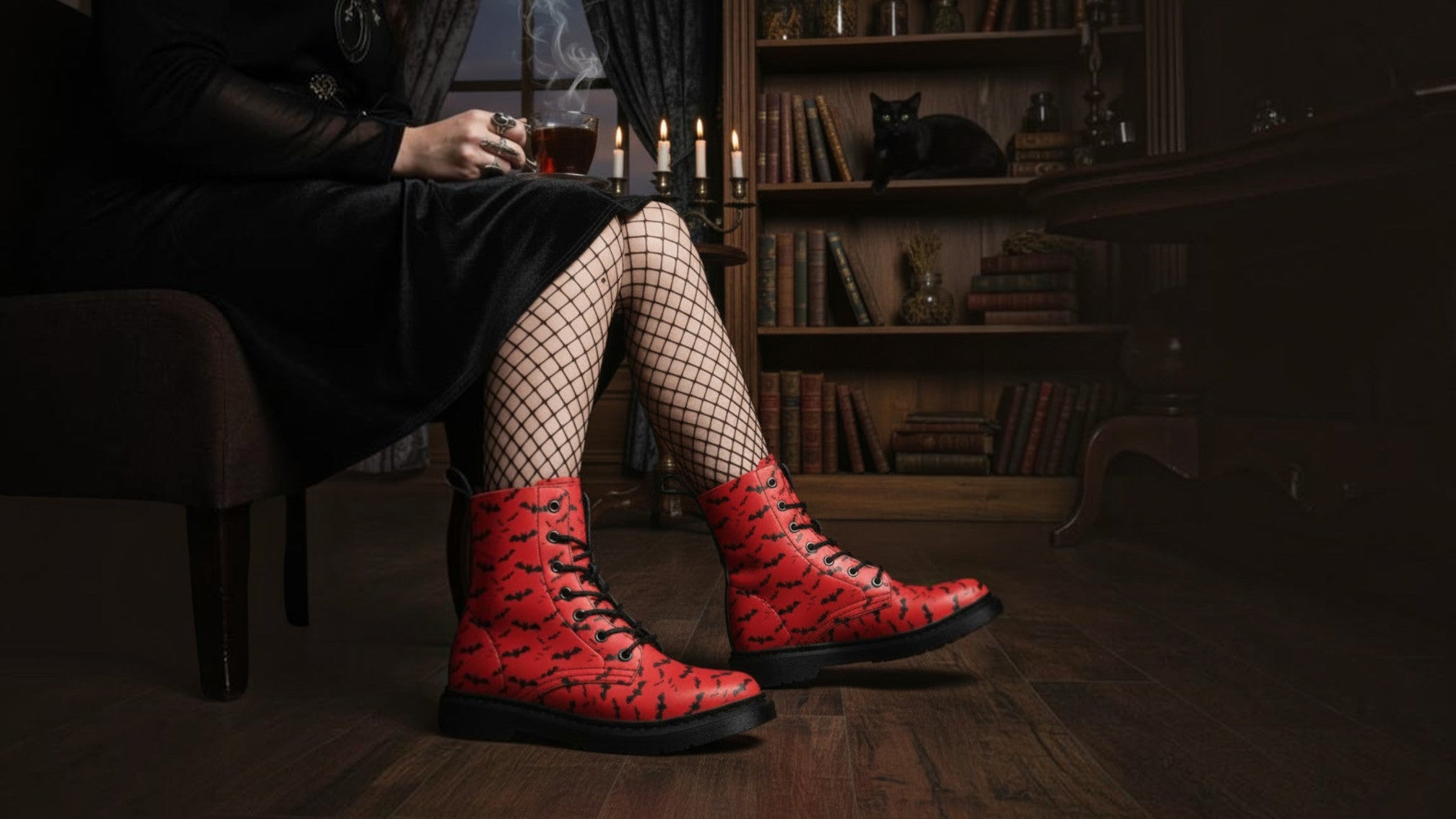A person seated in a dark room wearing red combat boots with a black bat pattern, black fishnet tights, and a black dress. The room has a bookshelf, candles, and a dark atmosphere.