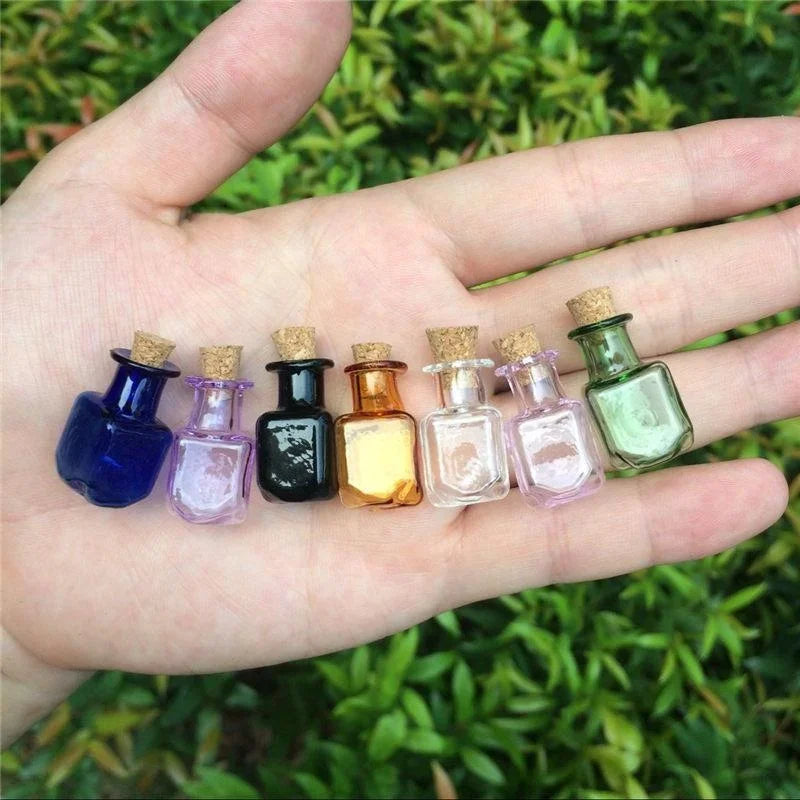 Small glass bottles with cork lids arranged on a hand against a green leafy background