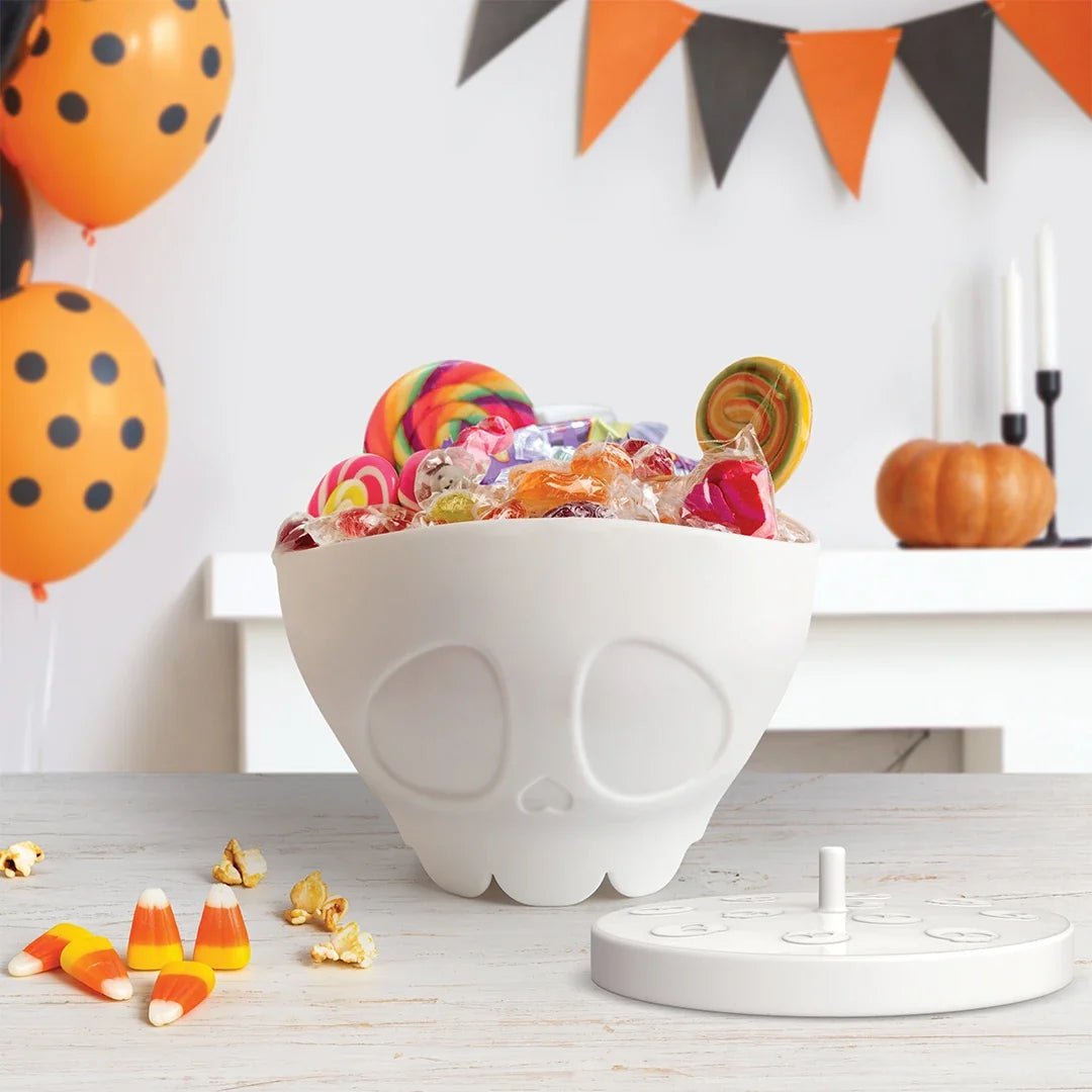 Halloween-themed candy bowl with colorful candies, balloons, and a pumpkin on a festive background.