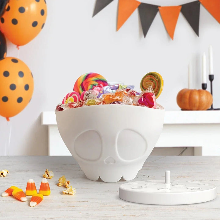 Halloween-themed candy bowl with colorful candies, balloons, and a pumpkin on a festive background.