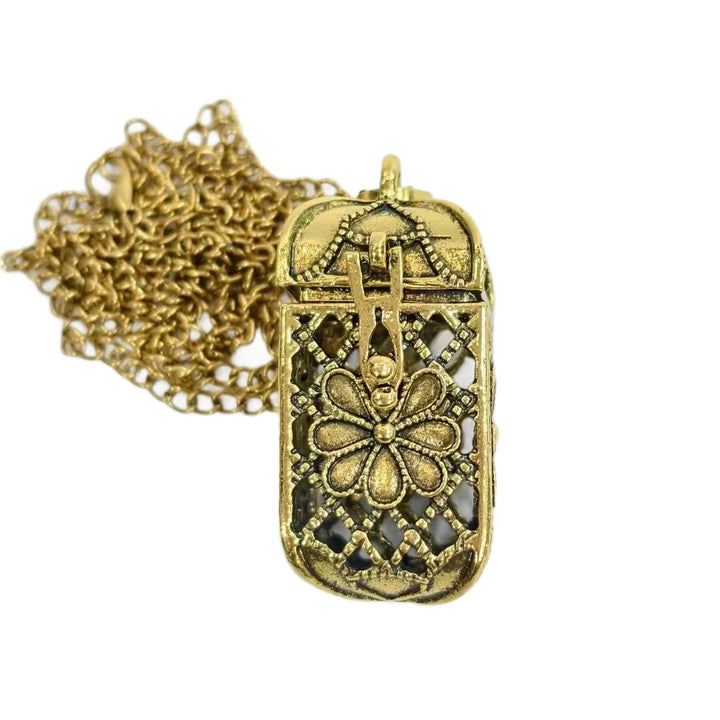 An antique gold filigree pendant necklace featuring a rectangular box design with a floral motif and openwork details, shown with its chain on a plain white background.