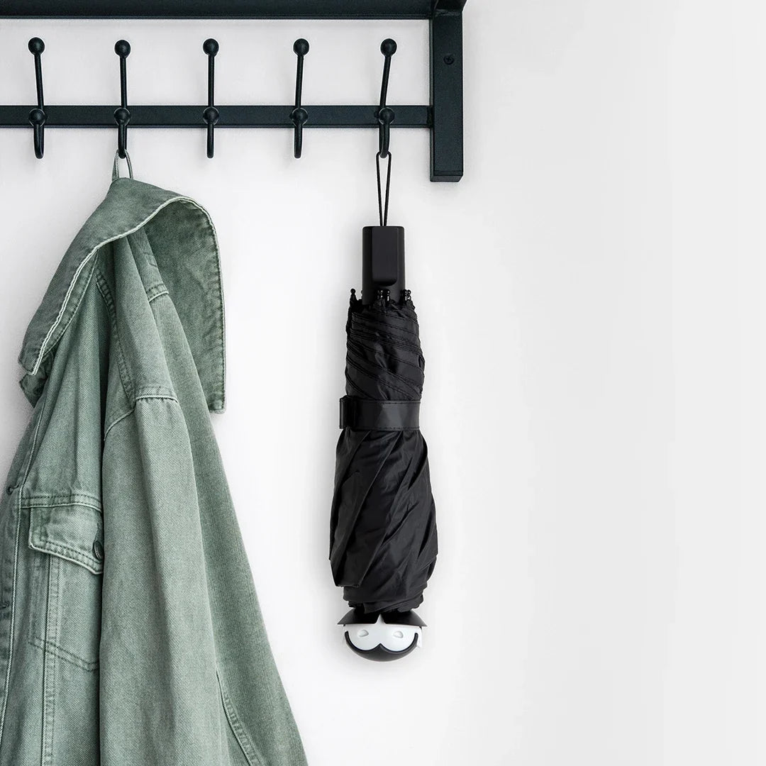 Black wall-mounted hook holding a jacket and an umbrella on a white background