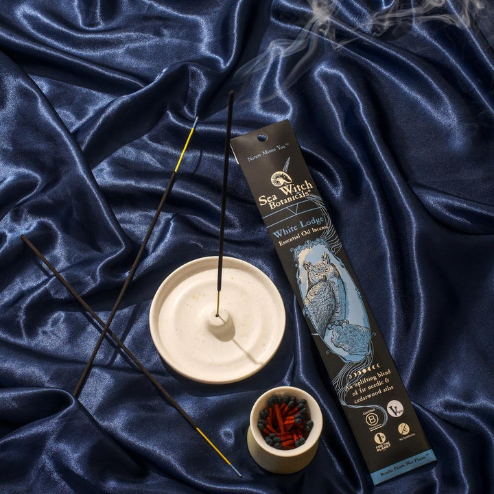 Incense gift set with two incense sticks, holder, and match cup on blue satin.