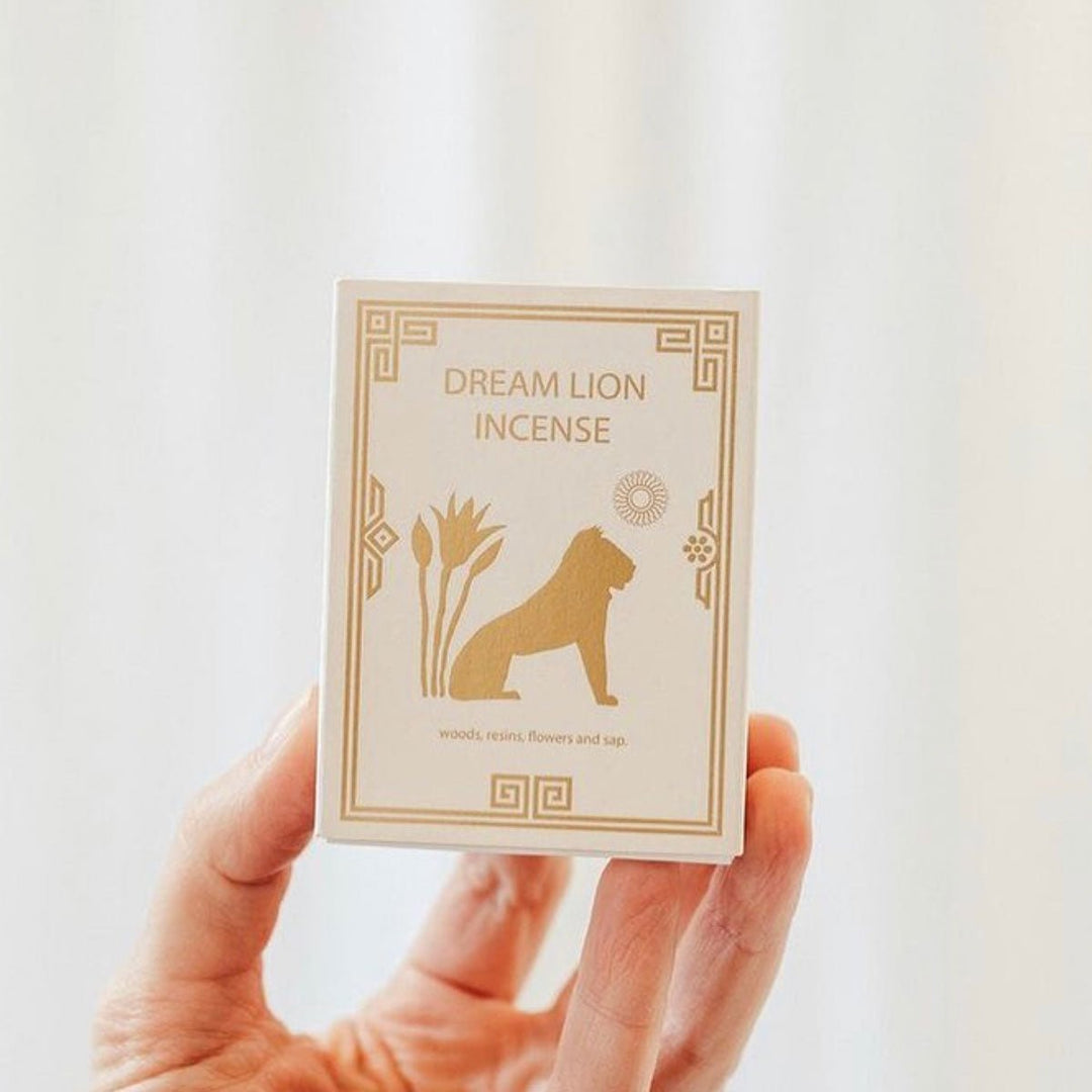 Nine treasures incense box held in hand, cream with gold geometric border and lion silhouette.