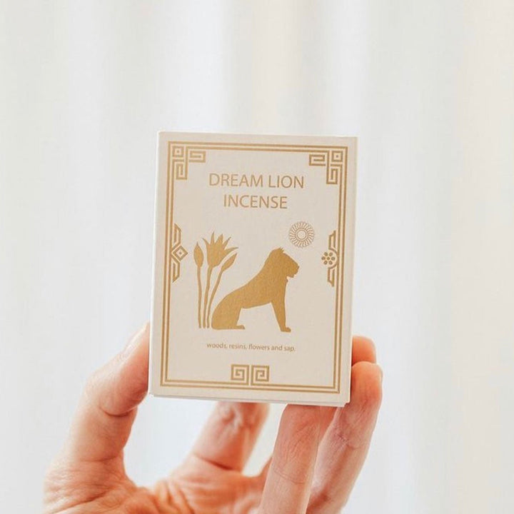 Nine treasures incense box held in hand, cream with gold geometric border and lion silhouette.
