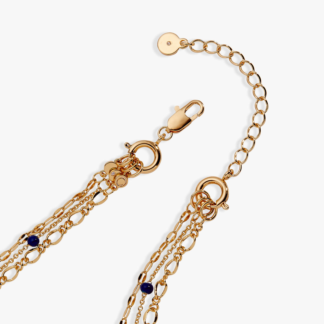 Gold chain bracelet with blue stones on a white background