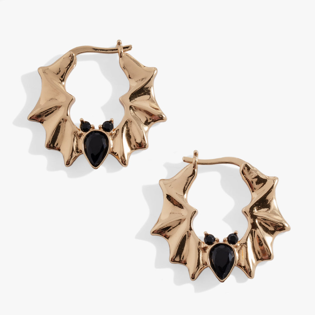 Gold bat hoop earrings with black heart-shaped stones on a white background