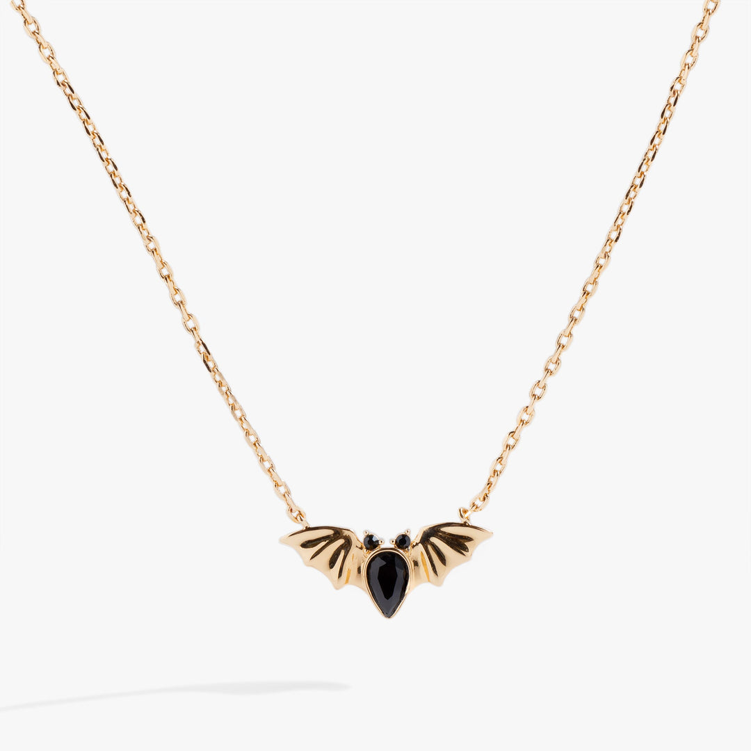 Gold necklace with a black pendant on a white background