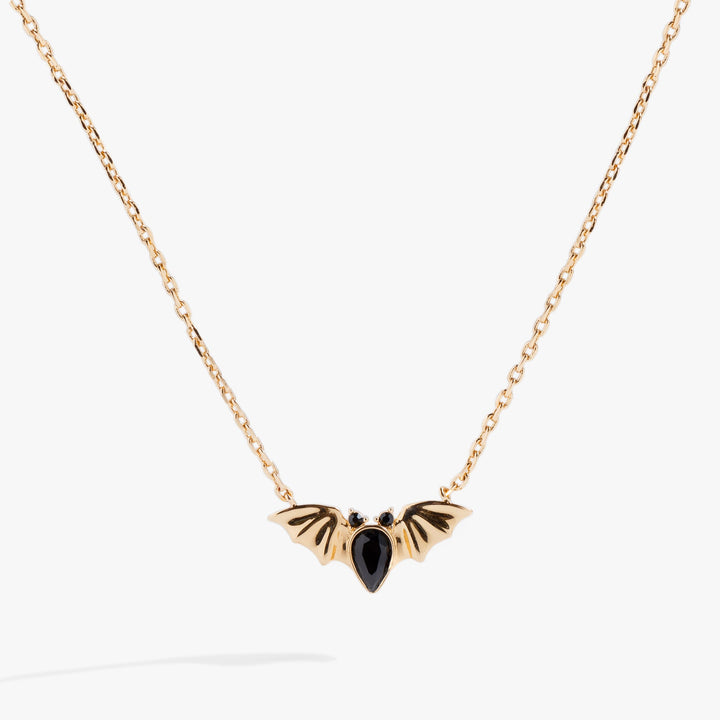 Gold necklace with a black pendant on a white background
