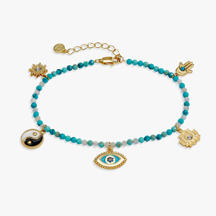 A gold-tone beaded bracelet with turquoise blue beads, featuring multiple charms including a Hamsa hand, an evil eye, a lotus flower, a yin-yang symbol, and a sun, displayed on a clean white background.