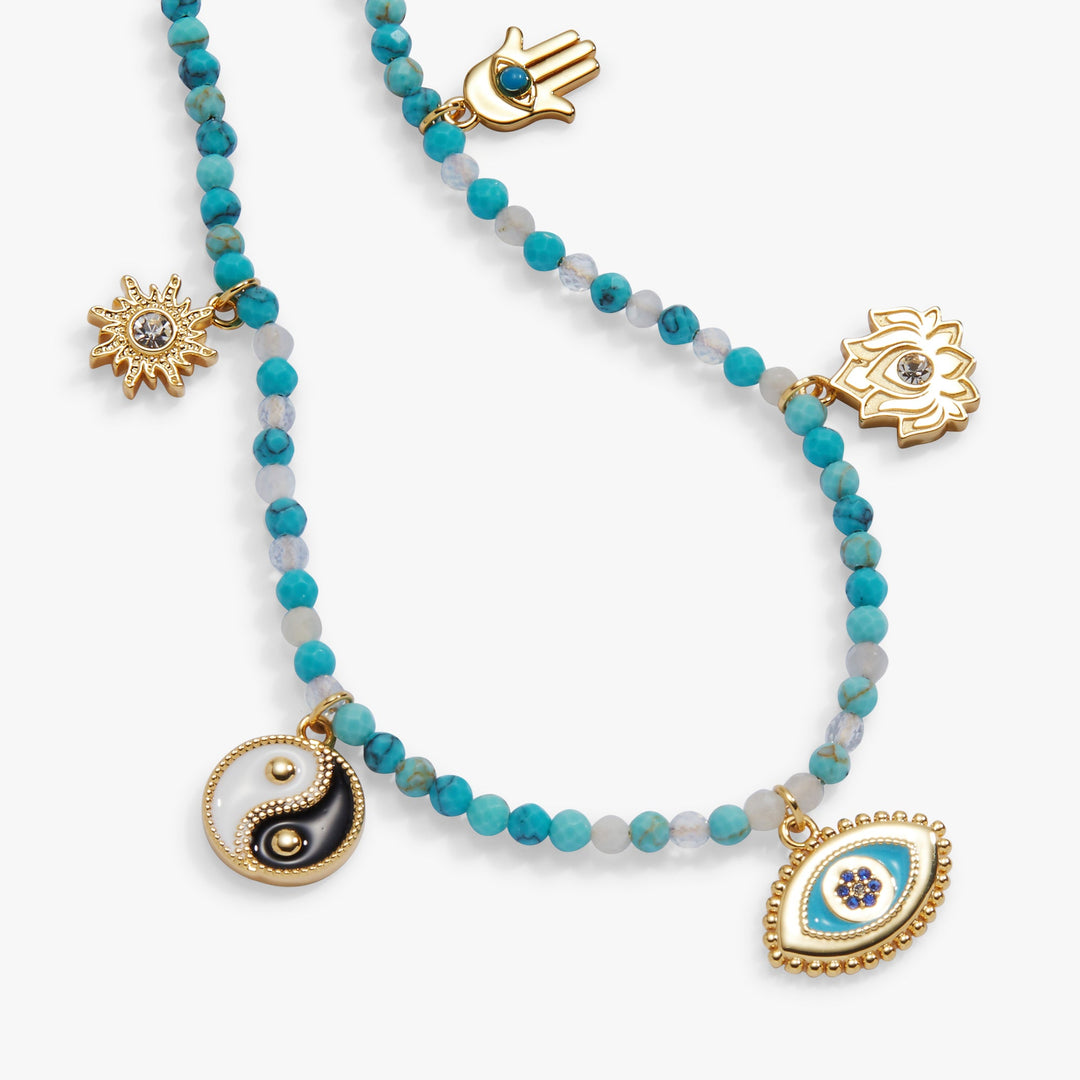 Necklace with various charms including a yin yang symbol and an eye design on a white background