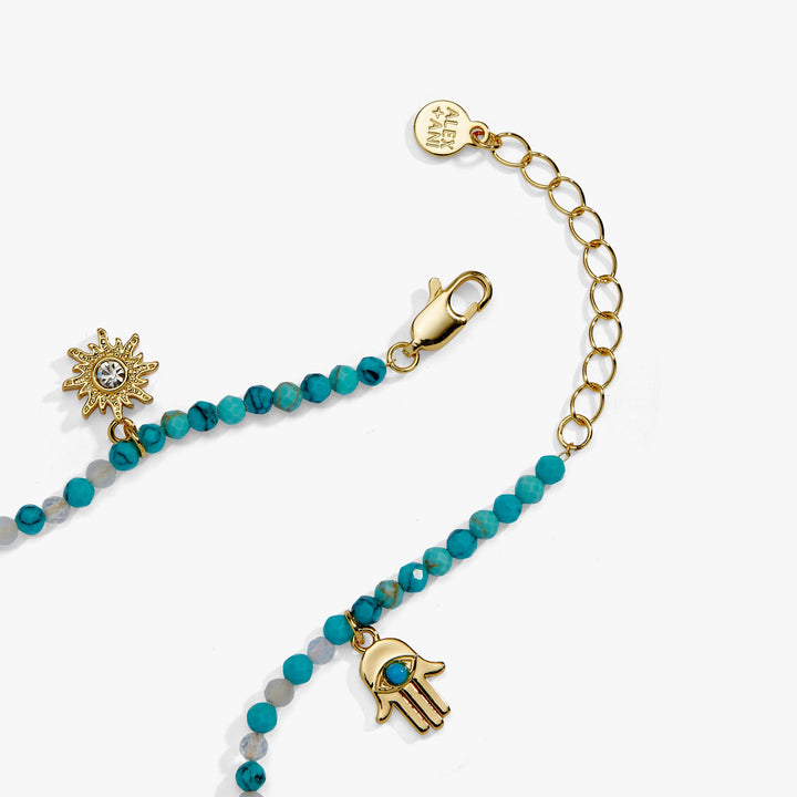 Bracelet with turquoise beads and gold charms on a white background