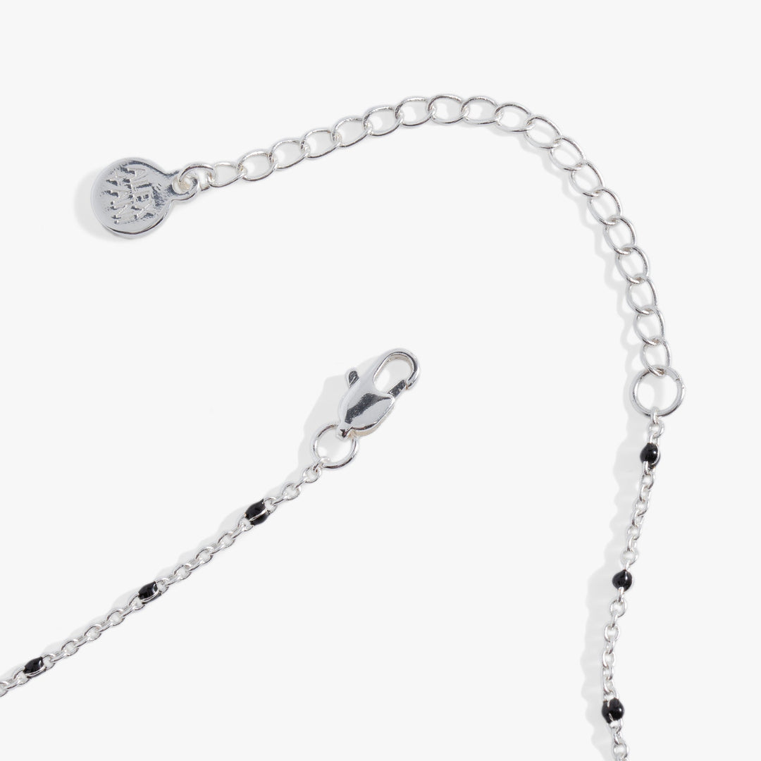 Silver chain bracelet with black beads on a white background