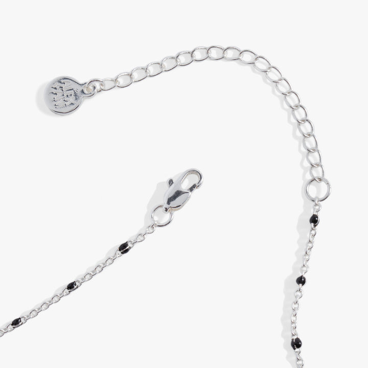 Silver chain bracelet with black beads on a white background