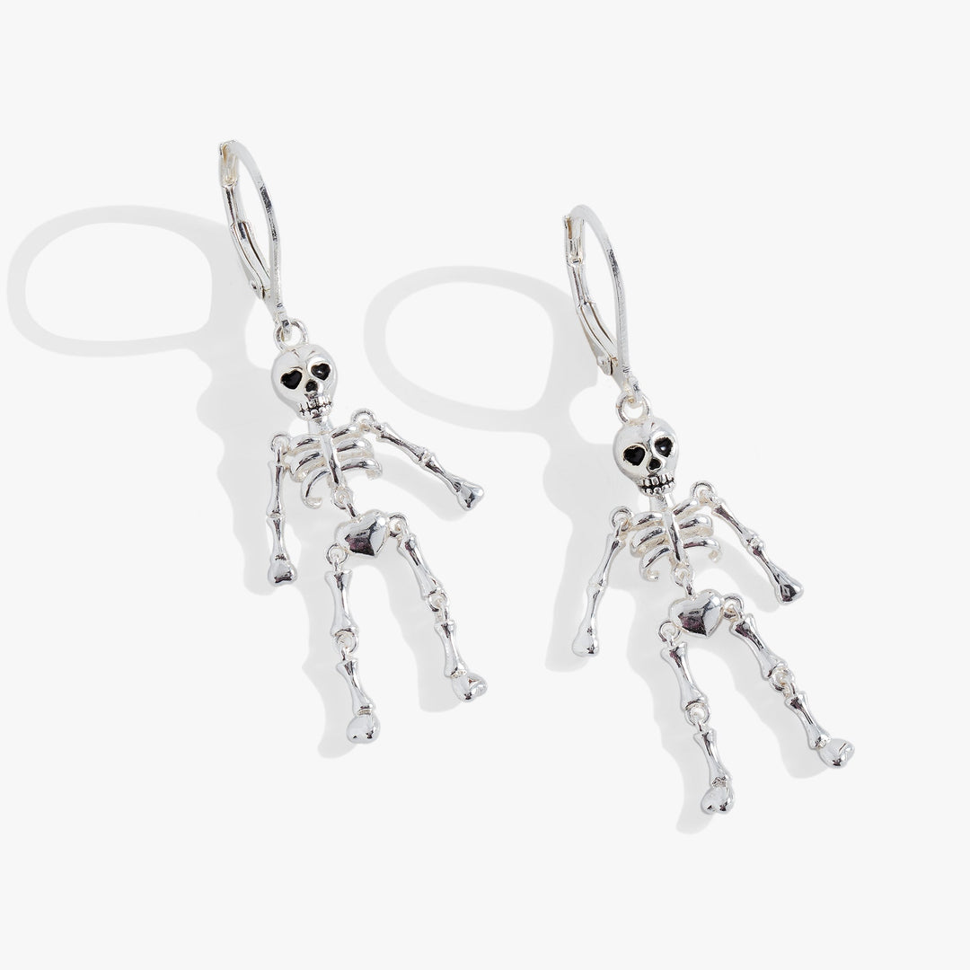A pair of silver skeleton drop earrings with detailed skull, rib cage, and bone charms, shown on a clean white background with soft shadows.